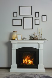 Stylish interior decorations on fireplace near white wall indoors