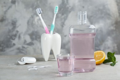 Mouthwash and other oral hygiene products on grey table, space for text