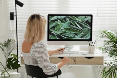 Woman working on computer at table in room, back view. Interior design