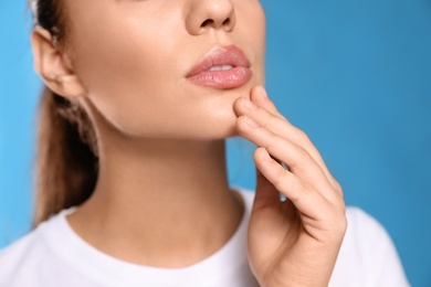 Photo of Woman with herpes on lips against light blue background, closeup