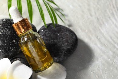 Photo of Bottle of face serum, spa stones and leaf in water on light background, closeup. Space for text