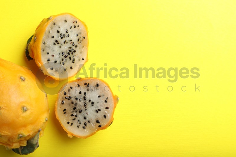 Photo of Delicious cut and whole dragon fruits (pitahaya) on yellow background, flat lay. Space for text