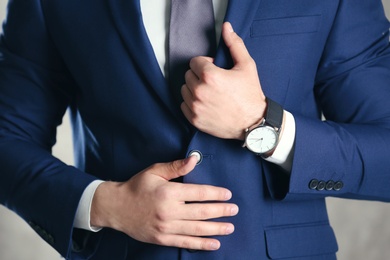 Man in formal suit with modern watch on light background, closeup