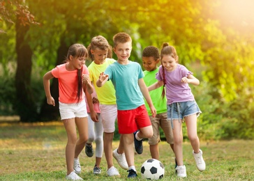 Image of School holidays. Group of happy children playing football outdoors 