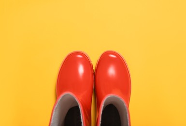 Red rubber boots on orange background, top view