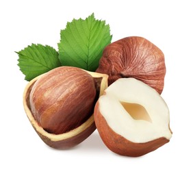 Tasty hazelnuts and green leaves on white background