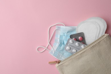 Bag with facial mask, pills and sanitary pads on pink background, top view. Space for text
