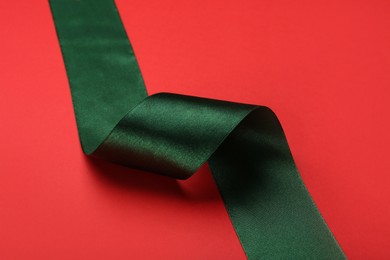 Beautiful green ribbon on red background, closeup