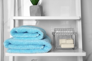 Fresh towels and soap bars on white shelf in bathroom