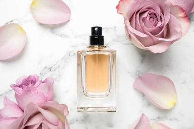 Photo of Flat lay composition with bottle of perfume and roses on white marble background