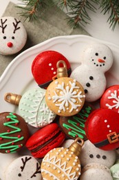 Beautifully decorated Christmas macarons and fir branches on white table, flat lay