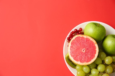 Photo of Choice concept. Top view of plate with fruits on red background, space for text