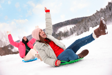 Happy friends having fun and sledding on snow. Winter vacation