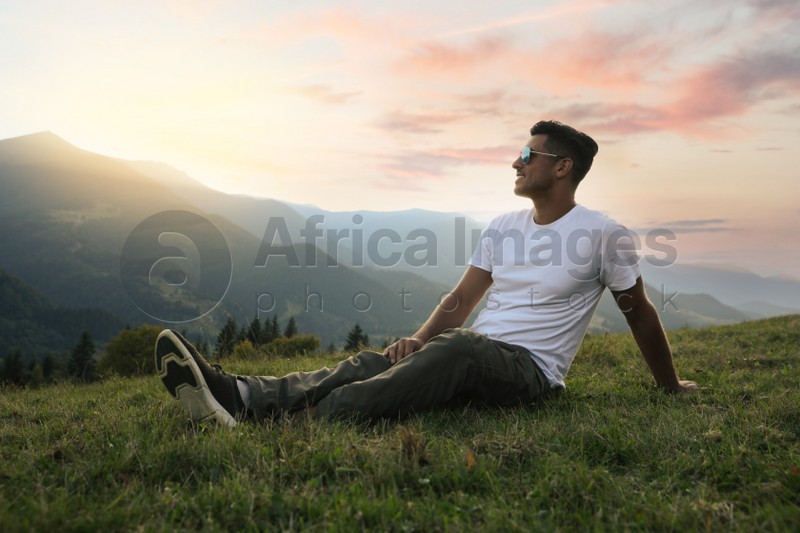 Photo of Handsome man enjoying beautiful mountain landscape at sunset