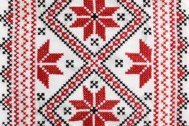 Traditional Ukrainian embroidery on white canvas as background, closeup. National handicraft