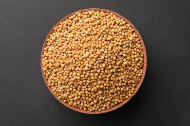 Bowl with mustard seeds on grey background, top view