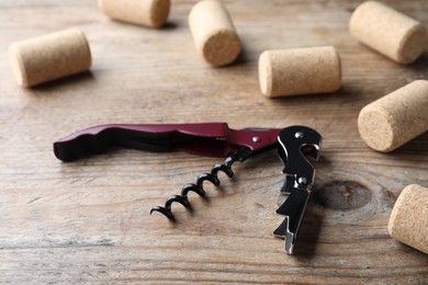 Opener with corkscrew and corks on wooden table