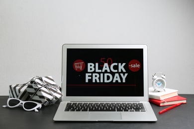 Composition with laptop and gifts on table against white background. Black Friday sale