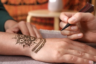 Master making henna tattoo on hand, closeup. Traditional mehndi