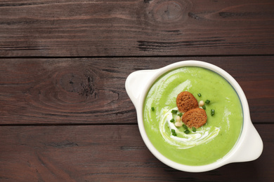 Tasty homemade zucchini cream soup on wooden table, top view. Space for text