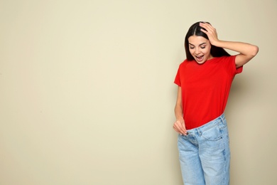 Slim woman in oversized jeans on color background, space for text. Weight loss