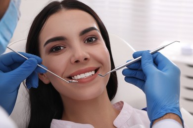 Dentist examining young woman's teeth in modern clinic