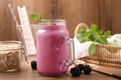 Delicious blackberry smoothie in mason jar, oatmeal and berries on wooden table