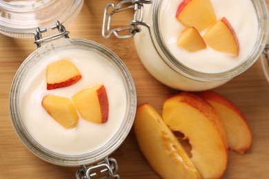 Delicious yogurt with fresh peach on wooden table, flat lay