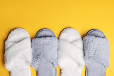 Different soft fluffy slippers on yellow background, flat lay. Space for text
