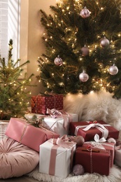 Gift boxes under small and big Christmas trees indoors