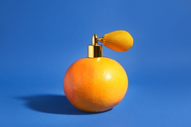 Grapefruit with vintage atomizer imitating perfume on blue background