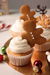 Tasty Christmas cupcake with gingerbread man and baubles on white table