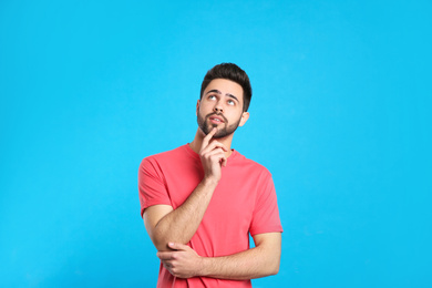 Pensive young man on light blue background. Thinking about difficult question