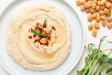 Tasty hummus with garnish served on white wooden table, flat lay