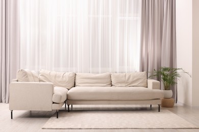 Photo of Comfortable sofa and window with beautiful curtains in room. Interior design
