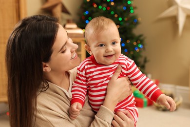 Happy you mother with her cute baby in room decorated for Christmas. Winter holiday