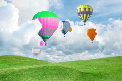 Fantastic dreams. Hot air balloons in sky with fluffy clouds over green meadow