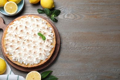 Flat lay composition with delicious lemon meringue pie on wooden table, space for text