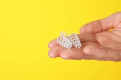 Woman holding anti-snoring device on yellow background, closeup. Space for text