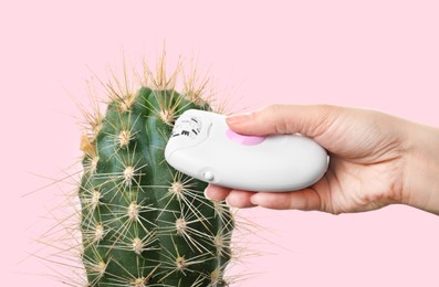 Hair removal concept.  Cactus and woman holding epilator on pink background, closeup 