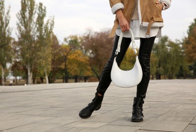 Stylish woman with trendy white baguette bag on city street, closeup