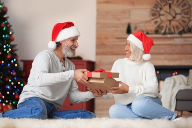 Happy couple opening Christmas gift at home