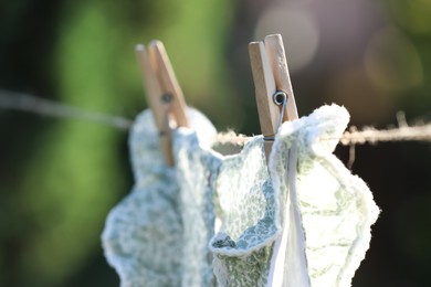 Washing line with drying dress against blurred background, focus on clothespin