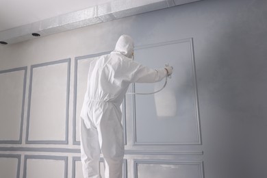 Photo of Decorator dyeing wall in grey color with spray paint