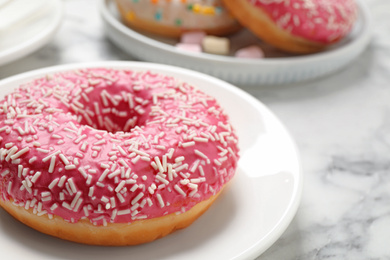 Yummy donut with sprinkles on white marble table, closeup