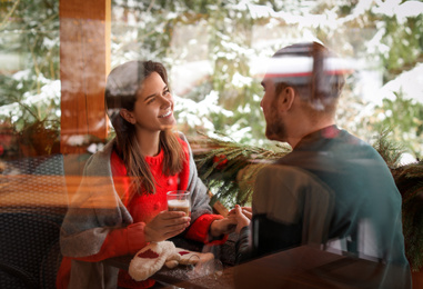 Photo of Lovely couple at table in cafe, view through window. Winter vacation
