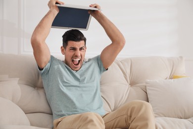 Emotional man with modern laptop at home