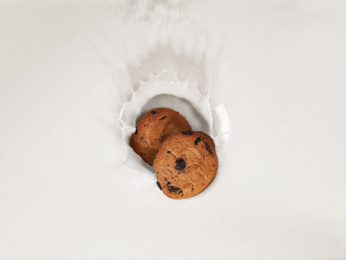 Cookies falling in milk with splashes, top view