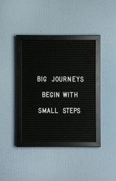 Photo of Black letter board with motivational quote Big Journey Begin with Small Steps on color background, top view
