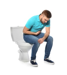 Young man suffering from digestive disorder on toilet bowl, white background